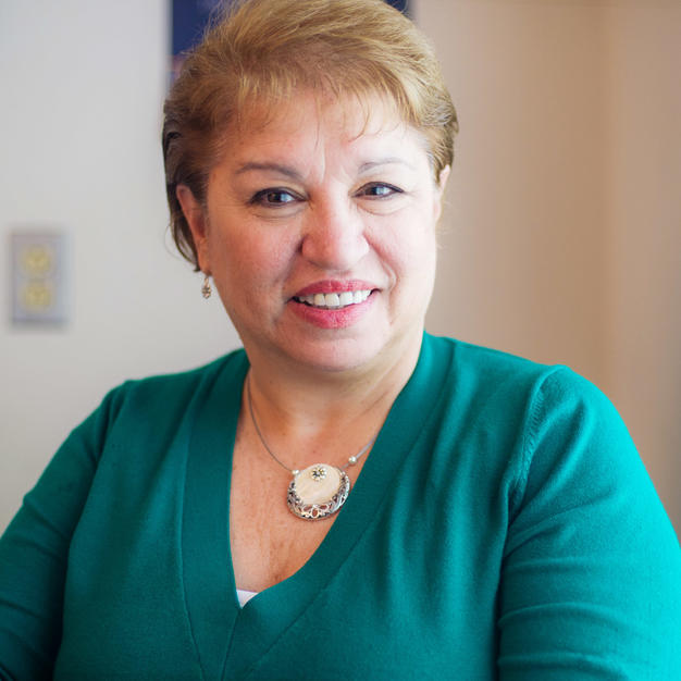 Older women wearing a green sweater smiling for camera in a doctor's office.