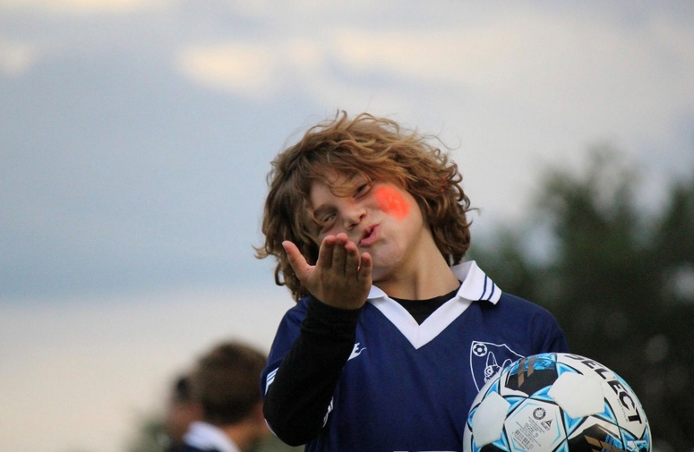 Child in soccer uniform blowing a kiss to the camera
