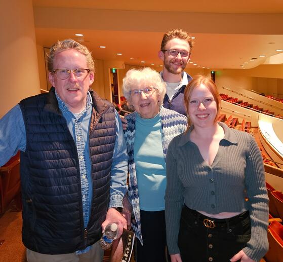 Group photo of a man, woman, and two young adults smiling inside a theater.