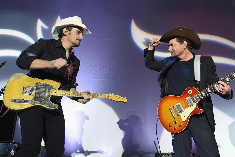 Michael J. Fox and Brad Paisley playing guitar on stage the annual 2017 Funny Thing Gala.