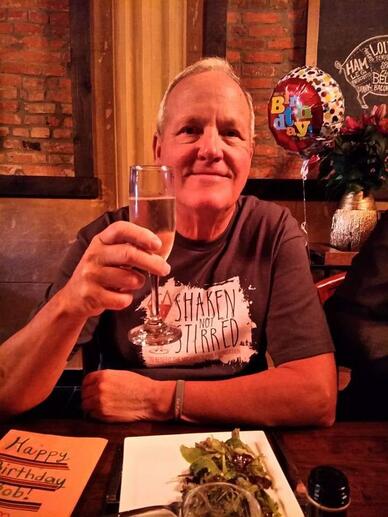 Bob Harmon smiling and holding up a glass. 