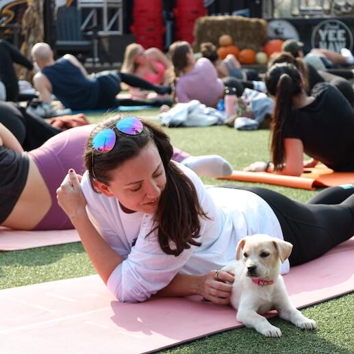 A young woman laying on a yog mat with a dog