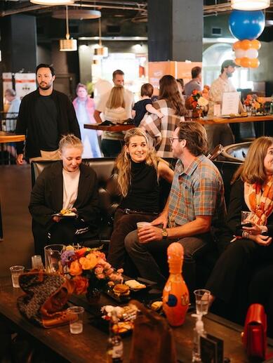 People sitting on a couch at bar area of a bowling alley