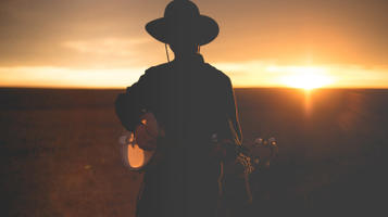 Silhouette of a man playing a guitar during the sunset