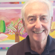 Jerry Pollack standing in front of some artwork of a landscape.