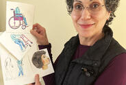 A woman holds up her illustrations.