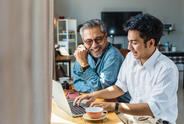 Two people smiling looking at laptop
