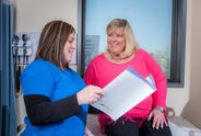 Female nurse and woman with Parkinson's in the doctor's office looking over a pamphlet.