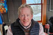 A man smiles indoors at a restaurant.
