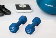 Set of weights next to blacks sneakers, a scale and blue ball. 