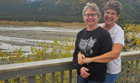 A couple pose in front of a mountain landscape. 