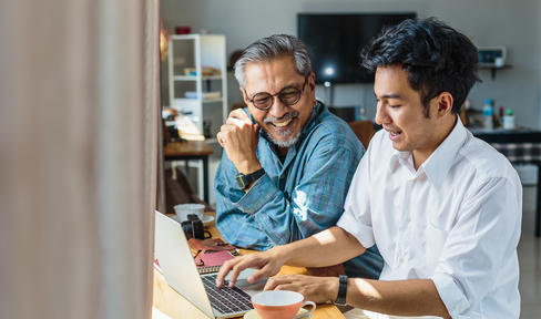 Two people smiling looking at laptop
