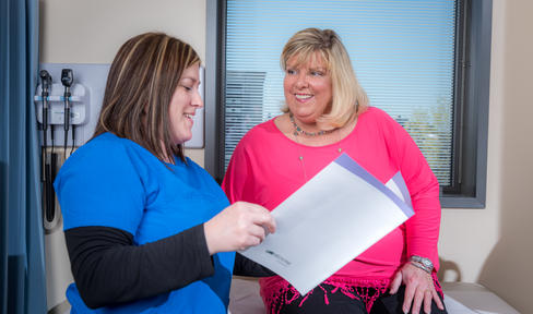 Female nurse and woman with Parkinson's in the doctor's office looking over a pamphlet.