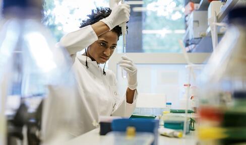 A researcher using a pipette while standing at a lab bench working in a research  laboratory.