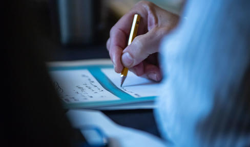Close-up of someone writing with a pencil
