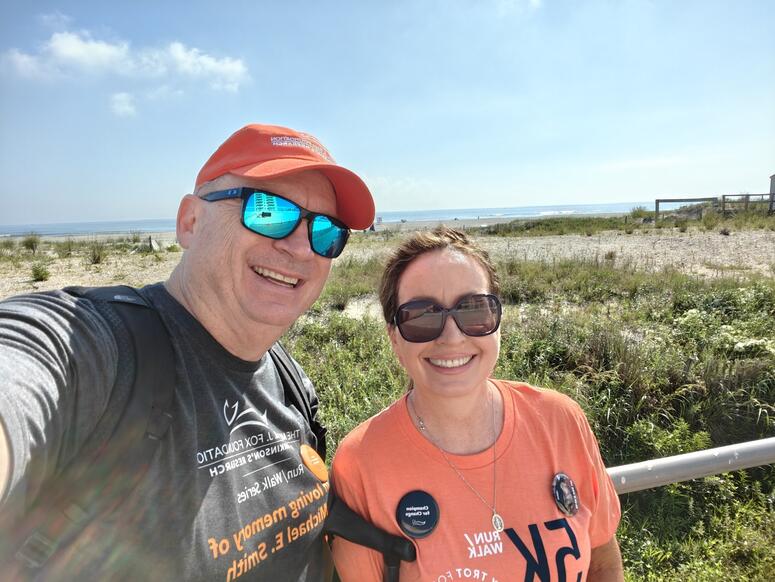 Anne and her husband pose in front of the Atlantic Ocean.