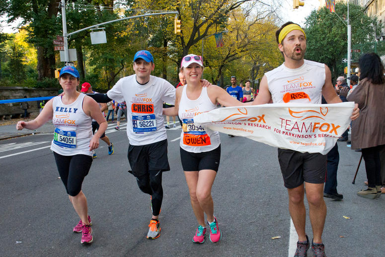Four Team Fox runners linking arms and carrying Team Fox banners