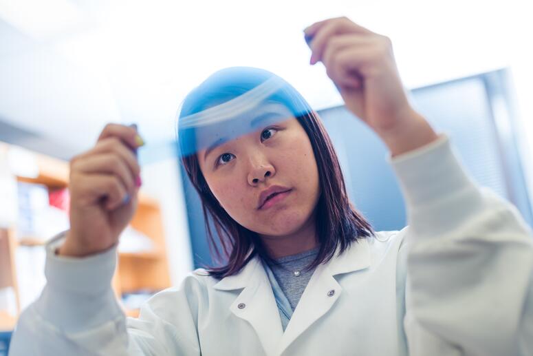 a person wearing a lab coat examines a piece of film