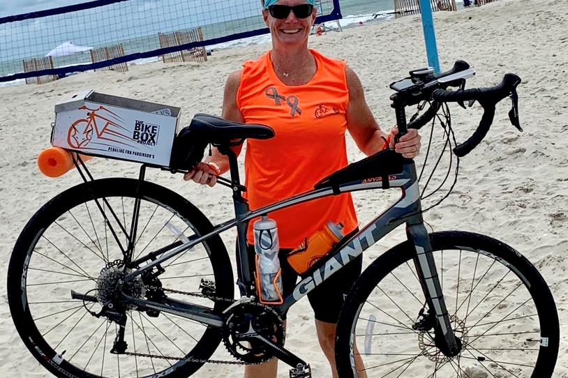 Bethany Richards holding bike on the beach.