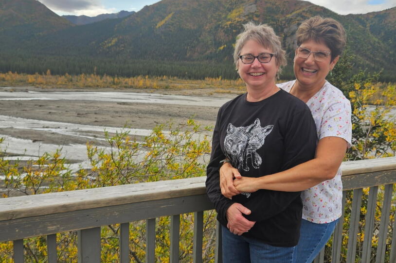 A couple pose in front of a mountain landscape. 