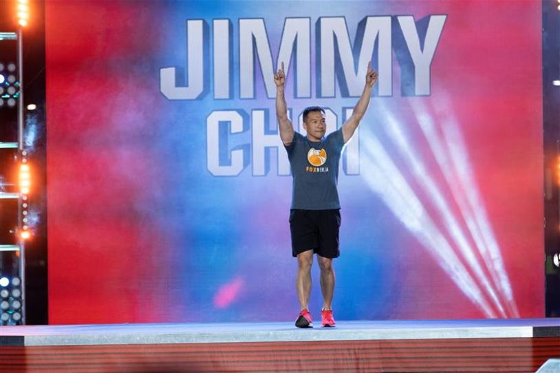 Jimmy Choi with his hands in the air cheering, while walking on to the American Ninja Warrior course.