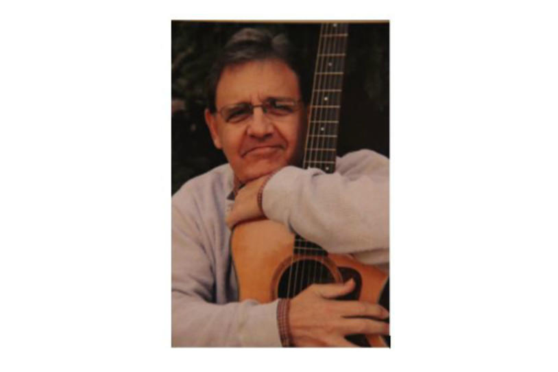 Person with Parkinson's Mark Robinson holding his guitar.