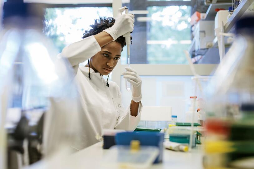 A researcher using a pipette while standing at a lab bench working in a research  laboratory.