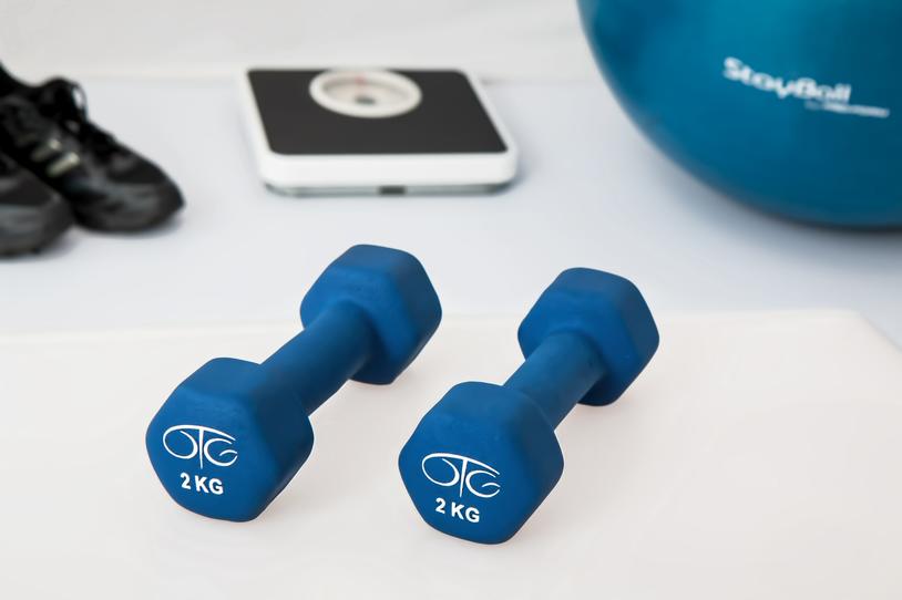 Set of weights next to blacks sneakers, a scale and blue ball.