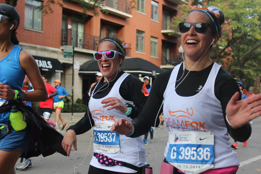 two women in team fox jerseys running and smiling