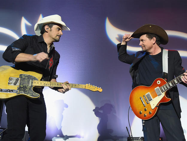 Michael J. Fox and Brad Paisley playing guitar on stage the annual 2017 Funny Thing Gala.