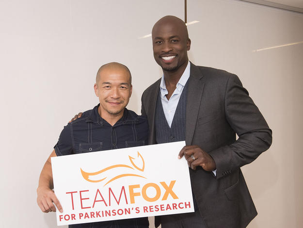 Patient Council member Jimmy Choi and Board member Akbar Gbajabiamila holding a Team Fox sign.