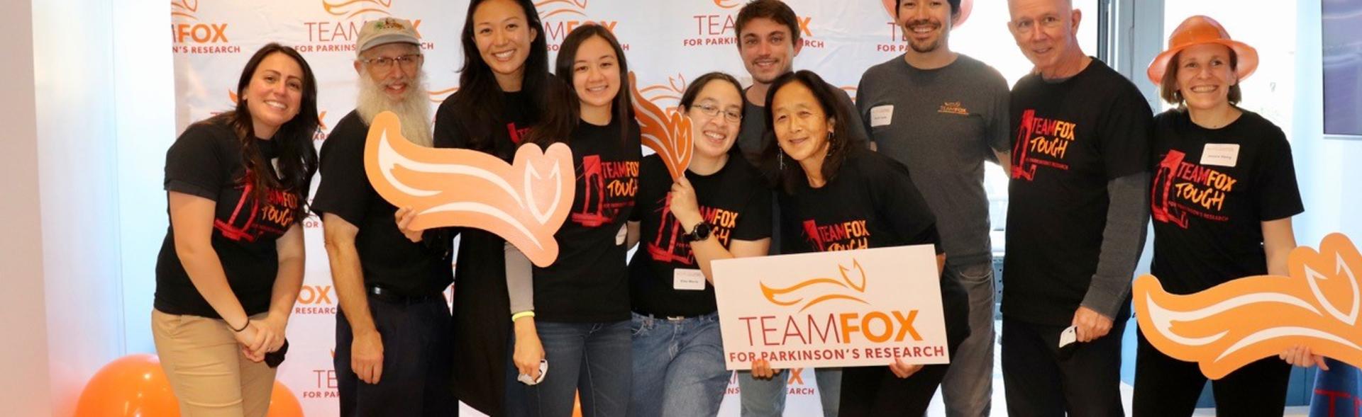 A group smiling with Team Fox signs & our fox logo.
