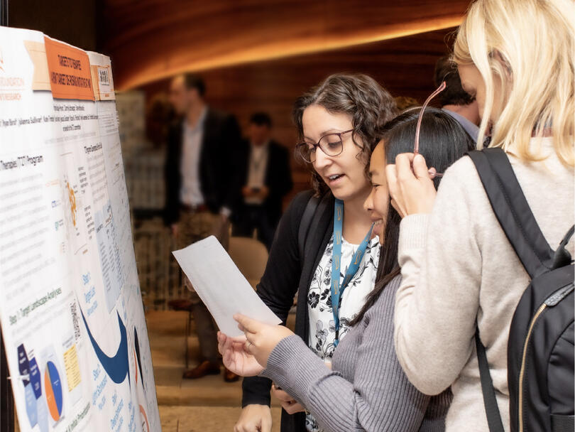 Three researchers looking at a presentation board at a conference