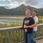 A couple pose in front of a mountain landscape. 