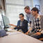 Three male researchers sitting or standing in front of a computer looking at a shared screen. 