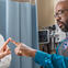 A patient in a doctor's office touching fingers with a physician while another physician observes the test.