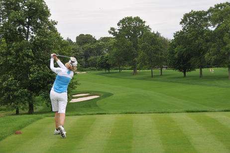 Female golfer swinging on the green.
