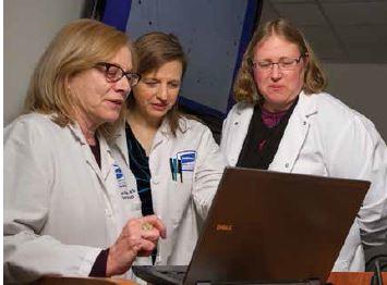Three Caucasian female doctors looking at a laptop. 